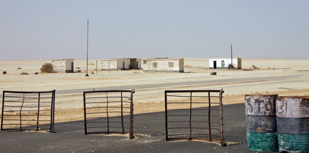 This is one of the many checkpoints in the Lybian desert: a few barriers and barrels on the road. It is forbidden to photograph the soldiers.