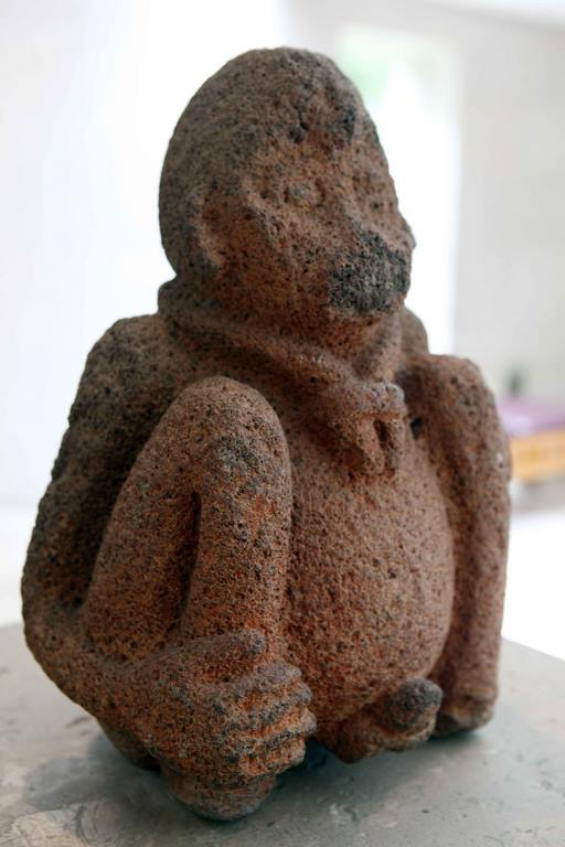 A seated monkey typical of Olmec culture, this figure with feline features wears a headdress that falls to the ears and a pectoral. The hands look strangely like feline paws. The transverse bands may have ritual or astronomical connotations. Los Soldados (Veracruz). 1200-1000 BC.