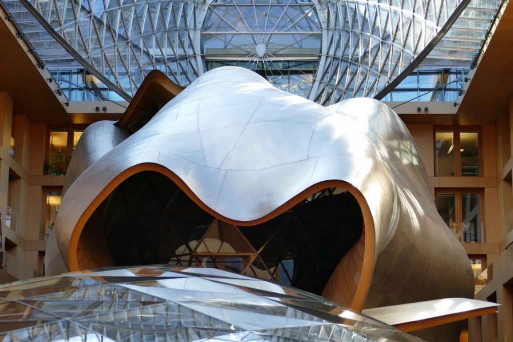 Dans l’atrium d'Axica, une sculpture spatiale monumentale de verre, de bois et de titane aux parois ondulantes, en forme de baleine, nous ouvre sa gueule : une prouesse de cet architecte visionnaire qui a également signé la fondation Louis Vuitton à Paris. 