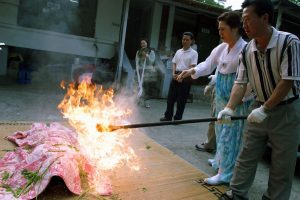 Corée du Sud. Rituel chamanique ou kut. Purification de la malade par le feu réalisée par l'assistante de la mudang.