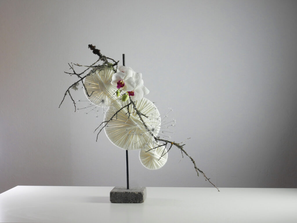 Ikebana. Sogetsu school. Contemporary style. Wool, branch with lichen and orchid. 