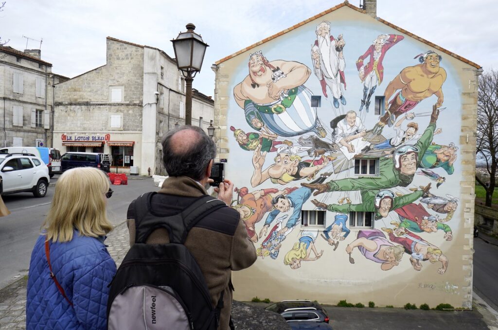 Angoulême. "Uderzo dans son cosmos" 10 Boulevard PasteurThis work, designed by François Boucq and produced by muralist Moon, pays tribute to the father of Asterix and Obelix. At the centre of this huge 200 m2 fresco, Albert UDERZO is seated at his drawing table, from which his heroes emerge. 2021.