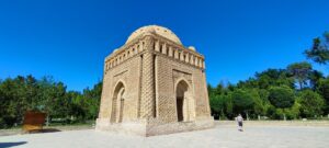 Boukhara. Le mausolée Ismaïl Samani au soleil couchant Vendredi 24 juin 2022. Un peu en retrait de la ville historique, situé dans un joli parc arboré, voici le mausolée Ismaïl Samani... que nous irons visiter seulement mon frère et moi. Nataliia nous a laissés à quelques hectomètres de là pour aller préparer le dîner... Non, mais je te jure ! Elles sont folles, ces Russes ! Surnommé « la perle de l’Orient », le mausolée des Samanides est resté pourtant longtemps oublié au fond d’un cimetière. Quand l’archéologue Chichkine le mit au jour en 1930, à l’occasion de l’aménagement du parc Samani, il était noyé au milieu d’autres tombes, enfoui sous plusieurs mètres de terre, ce qui lui valut d’être épargné par la tornade mongole et de traverser mille ans d’histoire. Aujourd’hui la nécropole a disparu, un parc a été aménagé autour du mausolée, et un bassin a été creusé pour lui redonner sa configuration originale. Les Ouzbeks y vénèrent le fondateur d’une des plus prestigieuses dynasties d’Asie centrale. La Perle de l’Orient est le témoin de l’âge d’or de Boukhara. Construit au début du Xe siècle par Ismaïl Samani, pour son père Akhmad, ce tombeau dynastique est un des plus anciens mausolées du monde musulman. Il abrite des descendants de cette lignée.