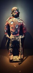 Haïti. Personnage fétiche bizango, début du XXIe siècle. Tissu rembouré, os (crâne humain), bois, miroir, métal. Ce fétiche porte les couleurs rouge et noire de la société secrète bizango.