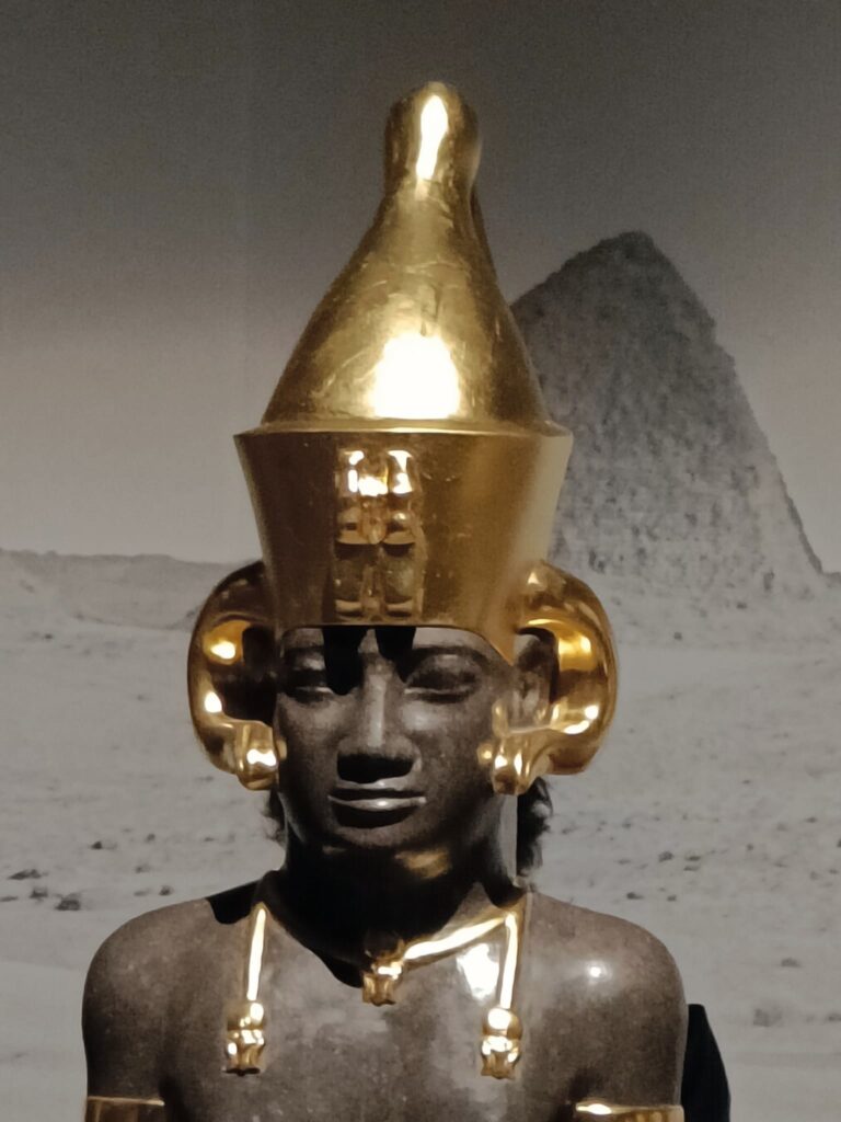 Réplique en résine de la tête du pharaon Anlamani avec des pendentifs représentant le bélier Amon.