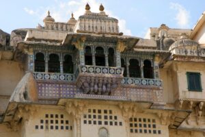 Inde. Udaïpur. La façade du City Palace se déploie comme une dentelle de pierre taillée, rythmée par une succession de balcons en encorbellement, appelés jharokhas, qui surgissent en légère avancée au-dessus du vide. B. Postel.