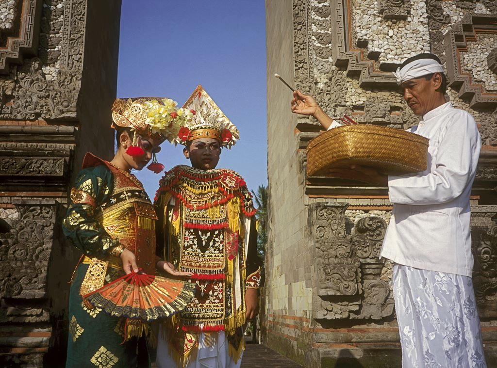 Indonesia. Bali. A priest or pemangku blesses two dancers in a temple before a sacred dance.  Sylvain Grandadam.