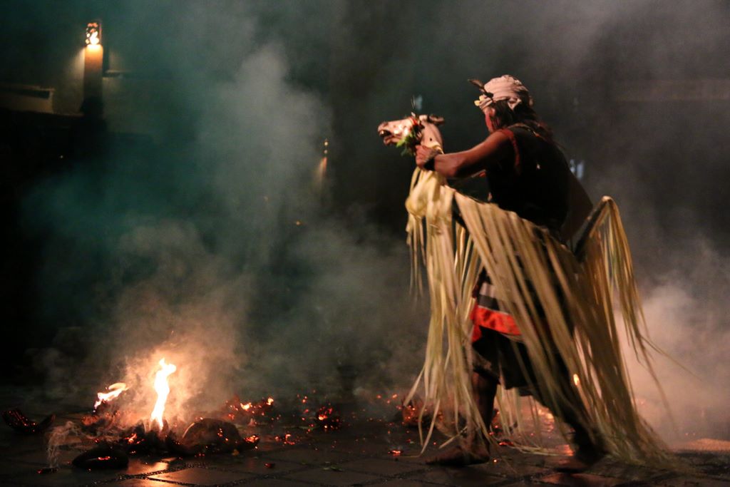 Indonesia. Bali. A Kecak tari dancer rides a symbolic horse made of wicker and coconut fibres across the brazier, kicking it into the flaming brandons. Batubulan/Commons.